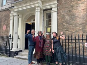 Four campaigners on a pavement in London, fists in the air.